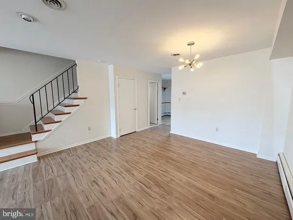 a view of an empty room with wooden floor and a ceiling fan