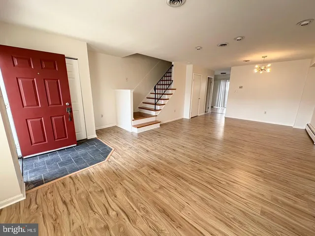 a view of an empty room with wooden floor and stairs