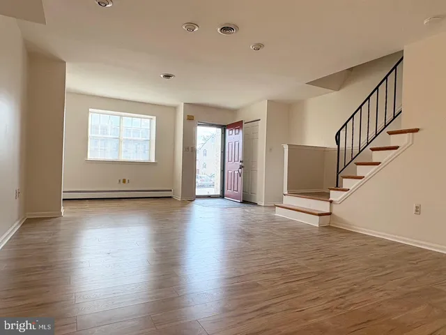 a view of an empty room with wooden floor and stairs