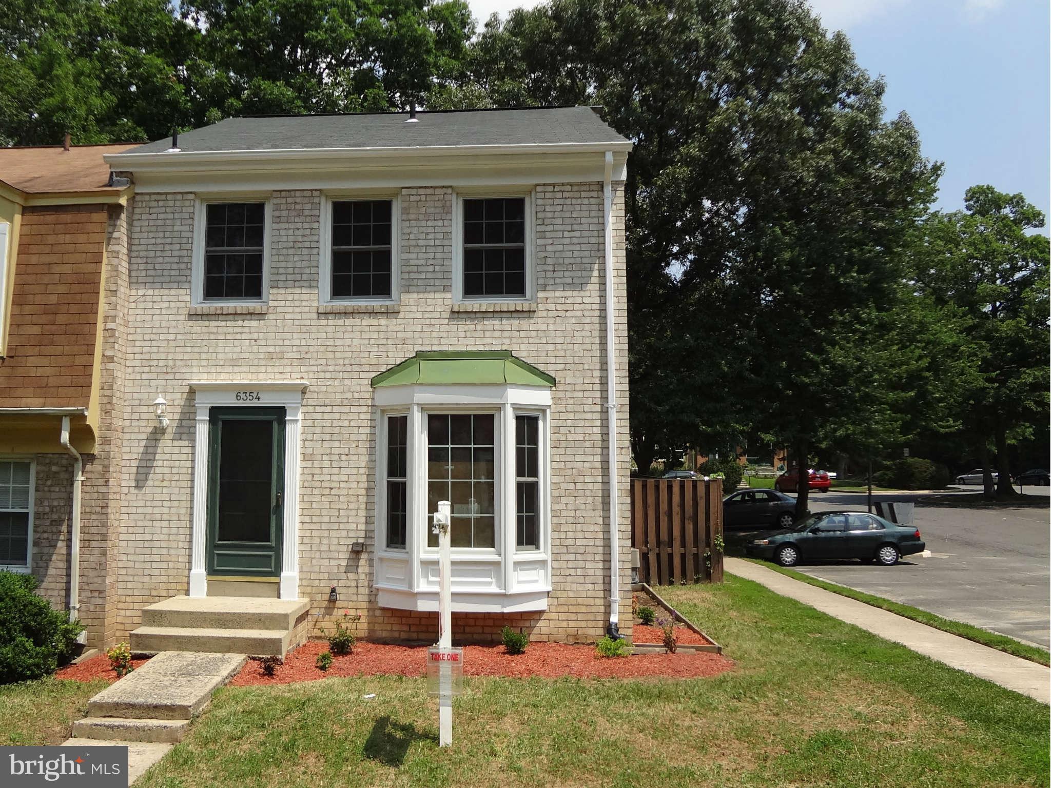 a view of a brick house with a yard and large trees