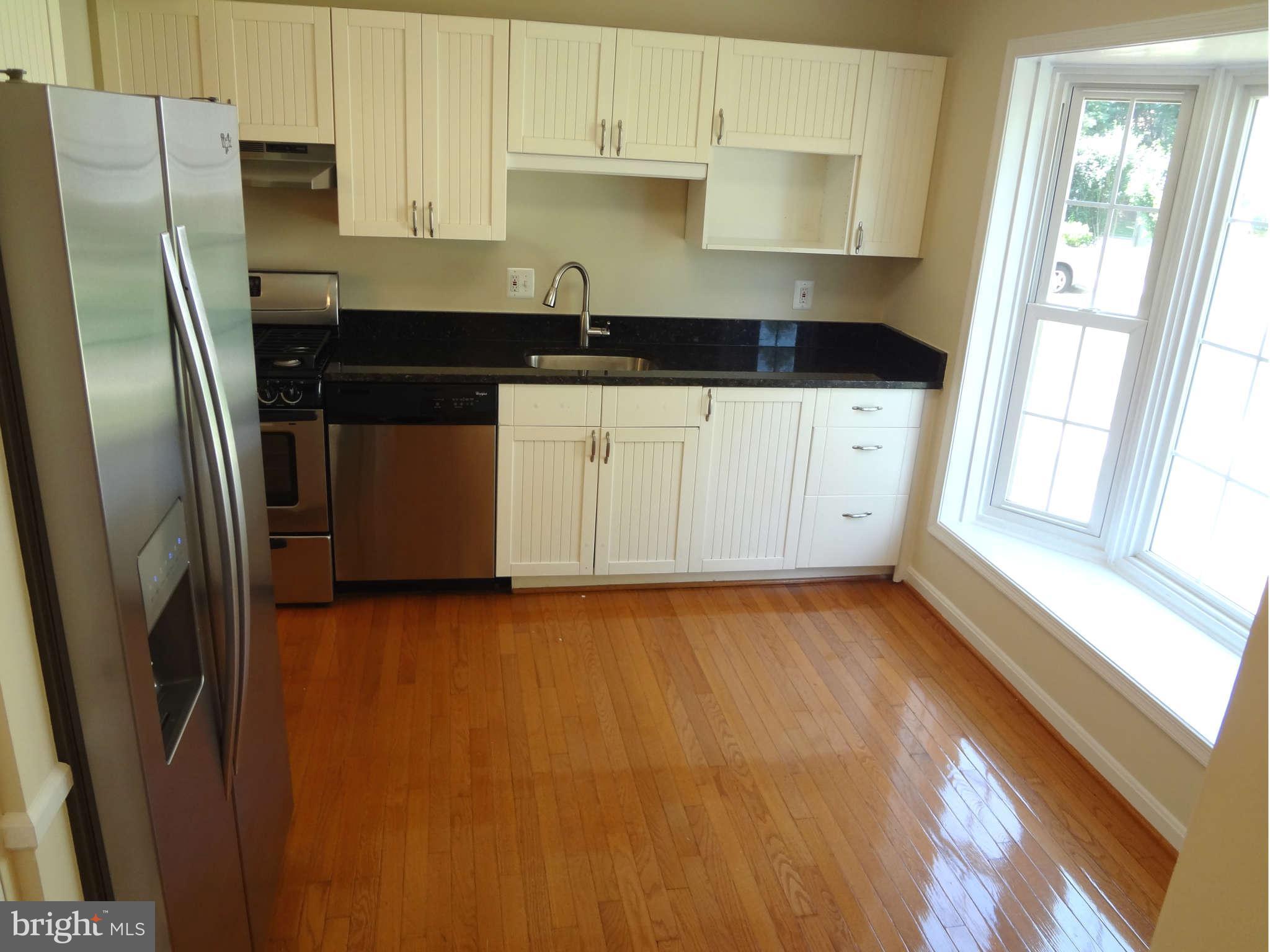 6354 Draco Street Burke, VA 22015 - Photo 7 of 21 a kitchen with granite countertop a refrigerator a sink and white cabinets