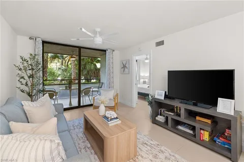 a living room with furniture a flat screen tv and a floor to ceiling window