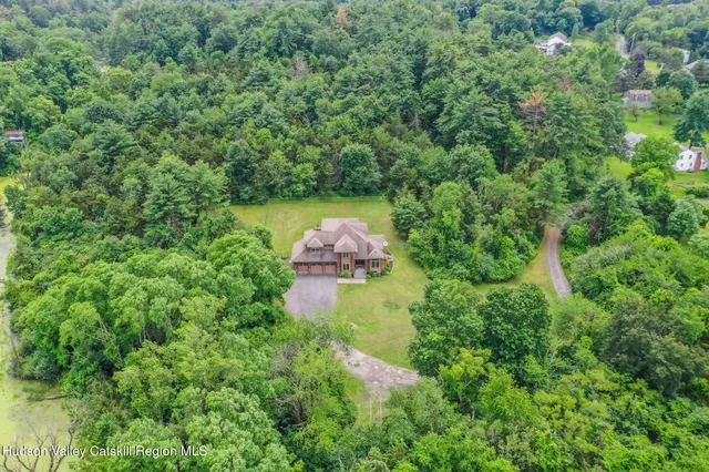 an aerial view of residential house with outdoor space and trees all around