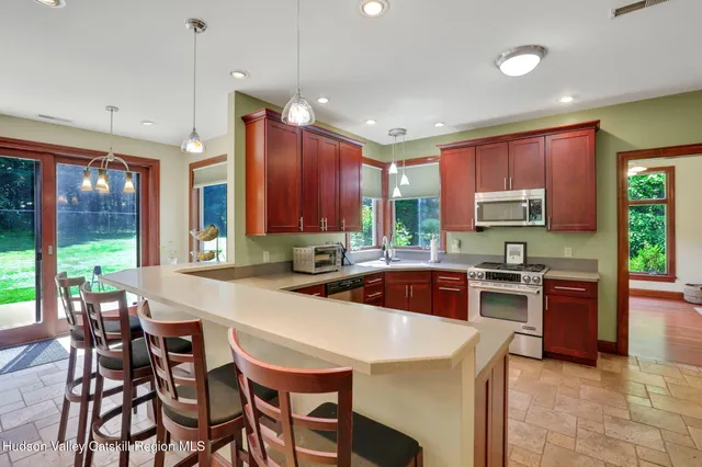 a kitchen with stainless steel appliances granite countertop wooden cabinets a stove top oven a granite counter space and a center island