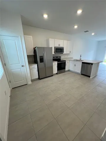 a large white kitchen with stainless steel appliances granite countertop a sink and cabinets