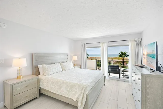 a bedroom with a large bed and a flat tv screen on dresser