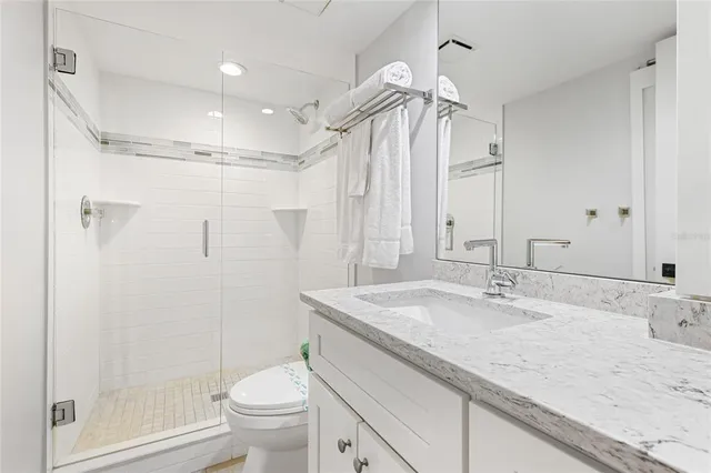a bathroom with a granite countertop sink a toilet a mirror and shower