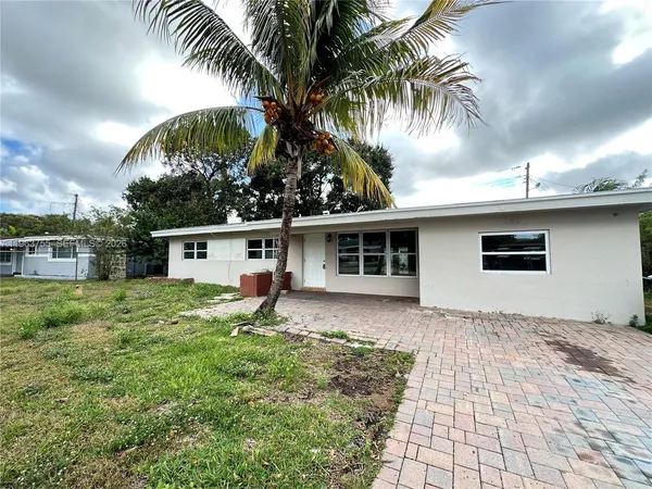 a view of a house with a yard and palm trees