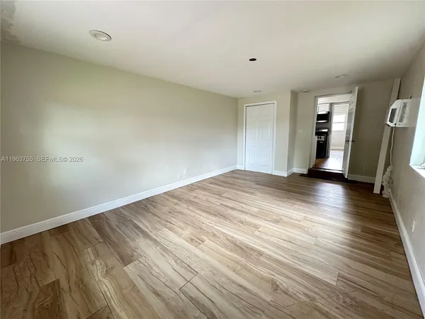a view of an empty room with wooden floor and a window