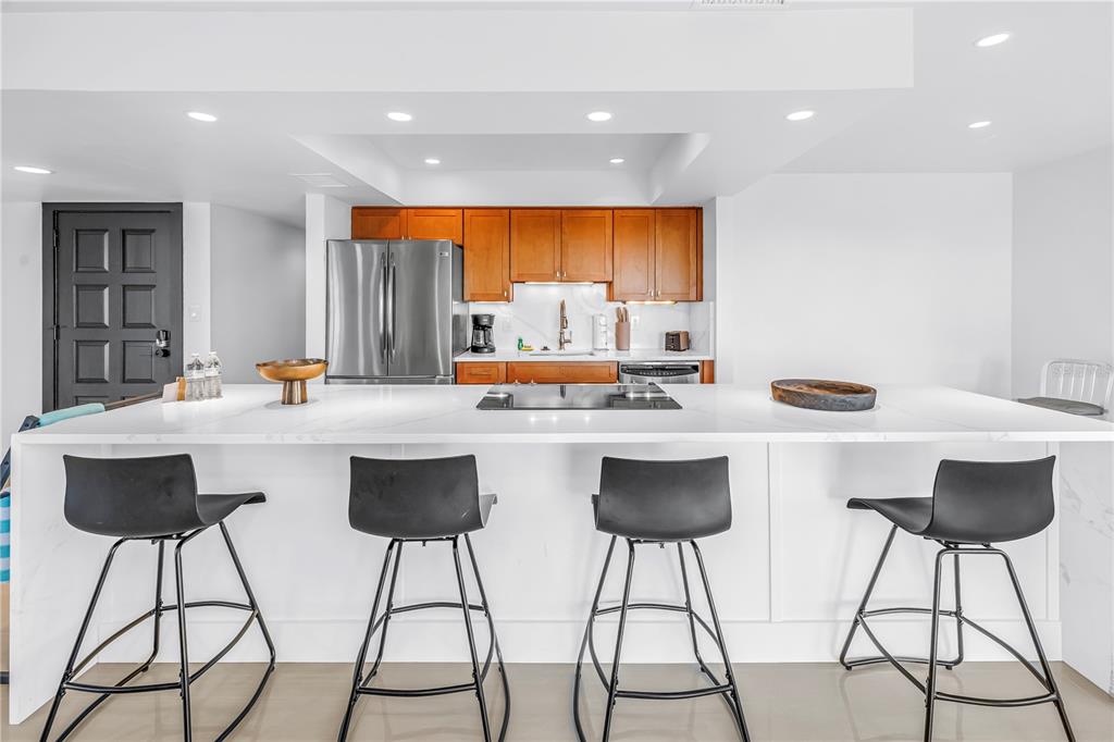 450 Beach Road, Unit 4 Sarasota, FL 34242 - Photo 9 of 64 a kitchen with stainless steel appliances a dining table chairs sink and white cabinets with wooden floor