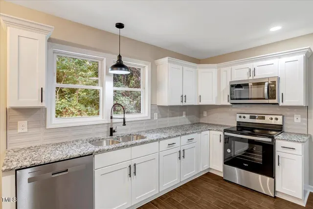 a kitchen with stainless steel appliances granite countertop a sink a stove a microwave and wooden cabinets