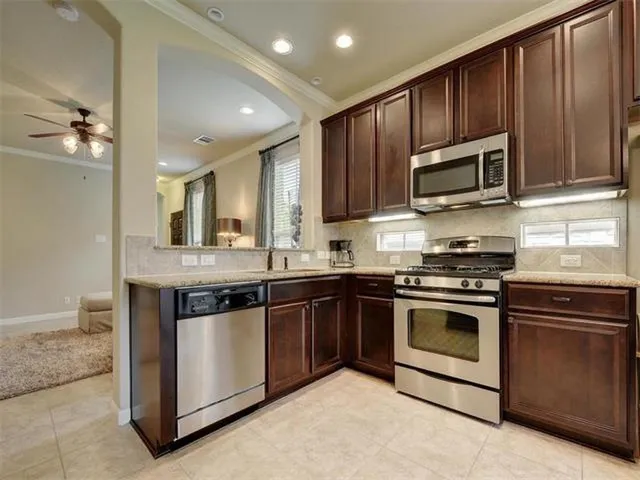 a kitchen with stainless steel appliances granite countertop wooden cabinets a stove a sink and dishwasher