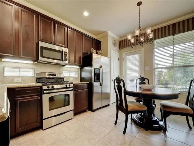 a kitchen with stainless steel appliances granite countertop a stove a sink dishwasher a refrigerator with a dining table and chairs