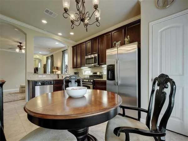 a kitchen with stainless steel appliances granite countertop a refrigerator a stove a sink a dining table and chairs