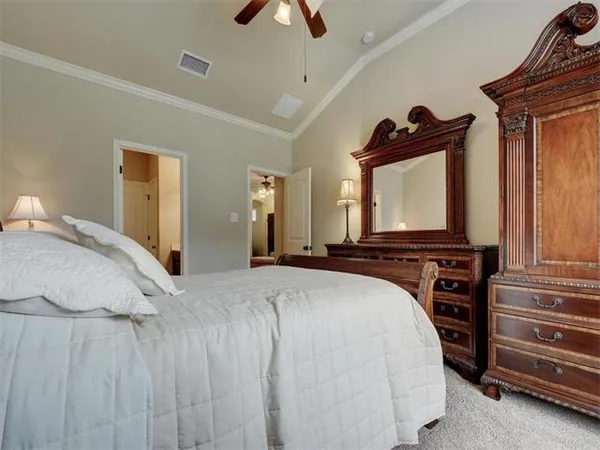 a bedroom with a bed a flat tv screen and dresser