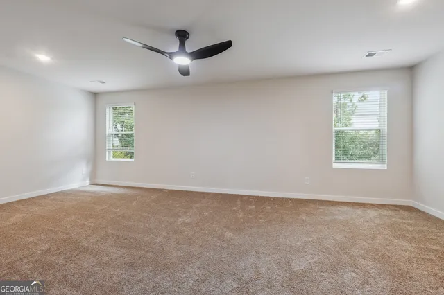 en empty room with windows and ceiling fan