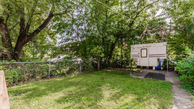 a view of backyard with a table and chairs and a large tree