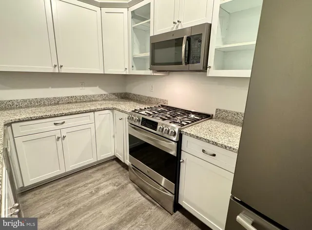 a kitchen with granite countertop white cabinets and stainless steel appliances