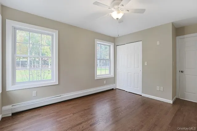 a view of an empty room with a window and wooden floor