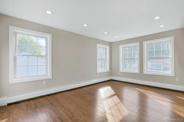 a view of an empty room with a window and wooden floor