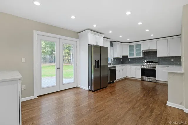 a kitchen with stainless steel appliances granite countertop a refrigerator microwave and wooden floor