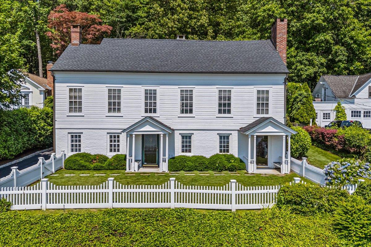 a view of a white house with a big yard and large trees