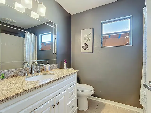 a bathroom with a granite countertop sink mirror vanity and toilet