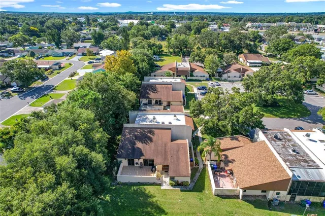 an aerial view of a residential houses with outdoor space and trees