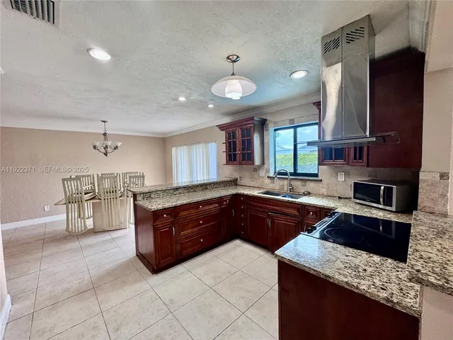 a kitchen with stainless steel appliances granite countertop a stove a sink and a microwave