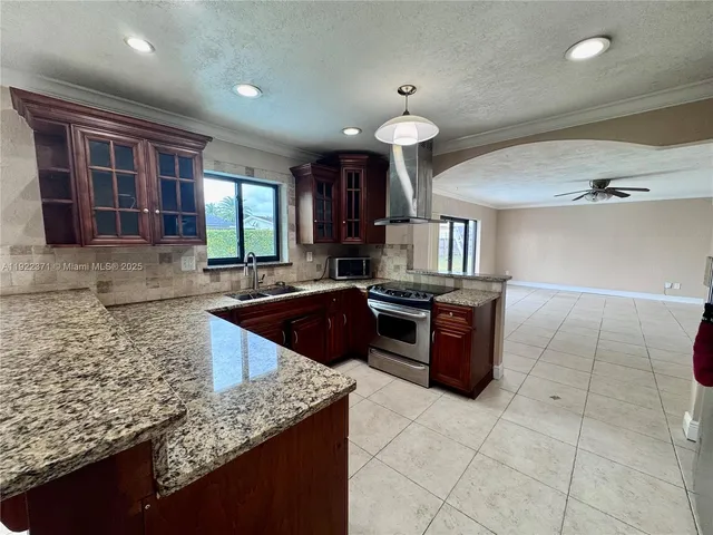 a large kitchen with granite countertop a stove sink and cabinets
