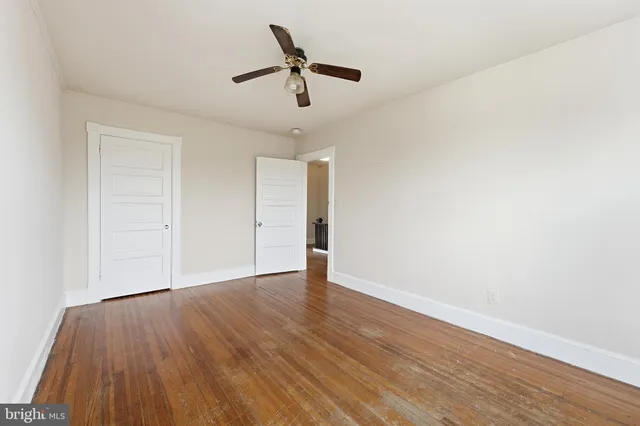an empty room with wooden floor ceiling fan and windows