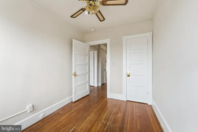 a view of empty room with wooden floor and ceiling fan