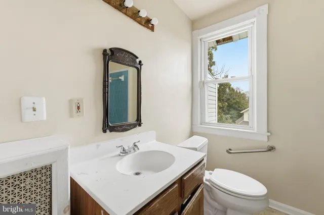a bathroom with a toilet sink vanity and mirror