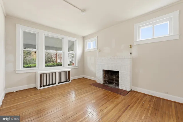 a view of empty room with wooden floor and fireplace
