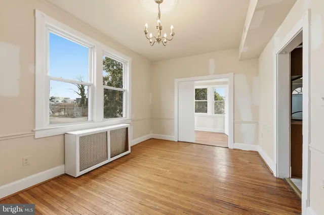 a view of an empty room with window and wooden floor