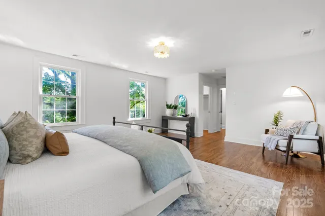 a spacious bedroom with a bed a table and windows