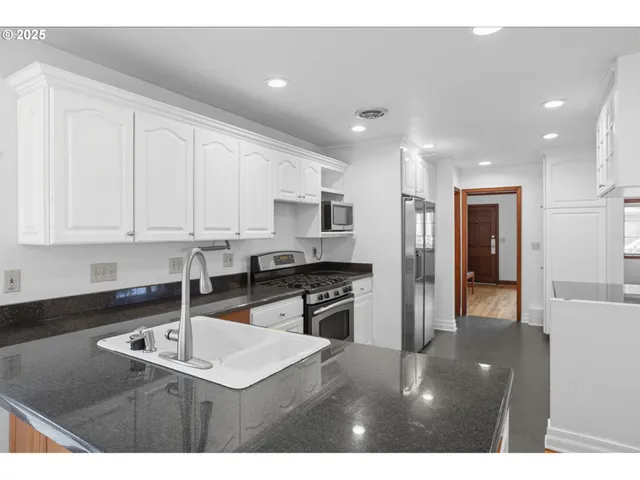 a kitchen with stainless steel appliances granite countertop a sink refrigerator and cabinets