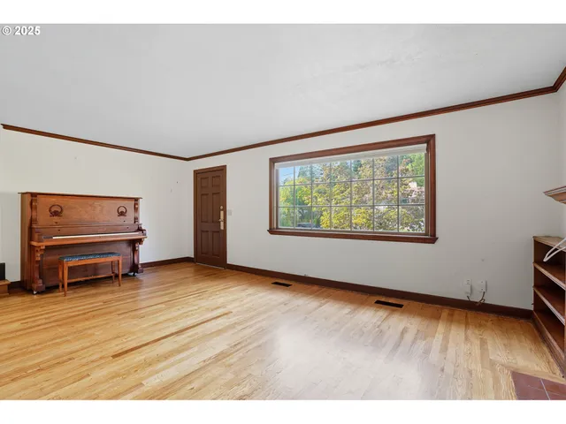 a view of an empty room with a window and dresser