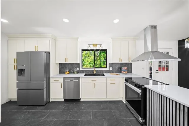 a kitchen that has a lot of white cabinets and stainless steel appliances