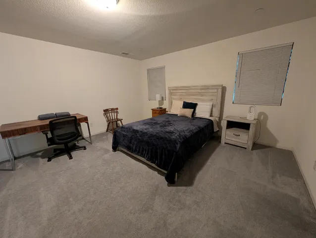 a bedroom with a bed and a lamp on desk