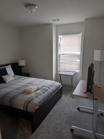 a bedroom with a bed a desk and chair next to a window
