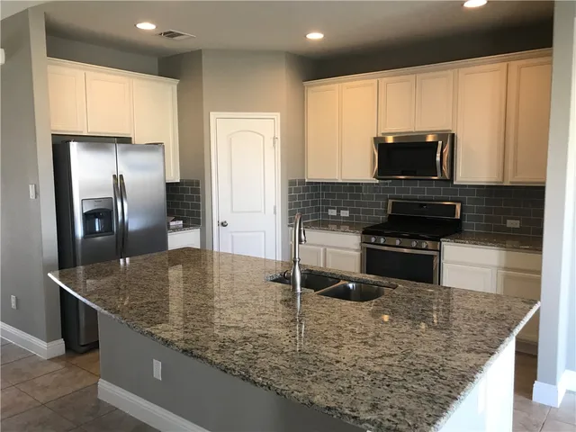 a kitchen with stainless steel appliances granite countertop a sink a stove and microwave