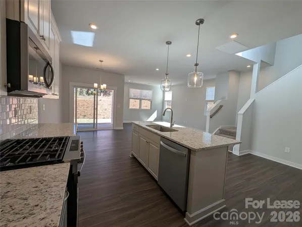 a kitchen with stainless steel appliances granite countertop a stove and a wooden floors