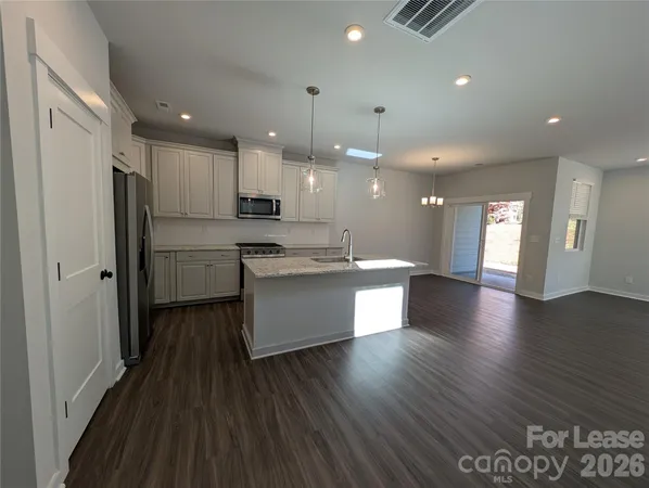 a large kitchen with stainless steel appliances kitchen island a large counter top and a refrigerator