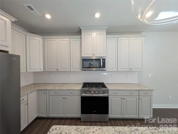 a kitchen with granite countertop white cabinets and stainless steel appliances