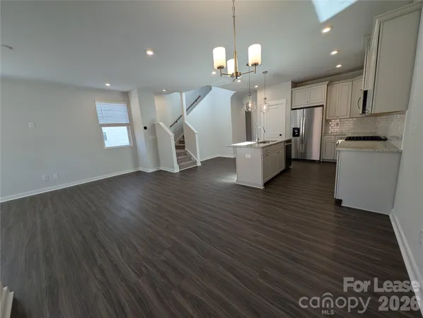 a large kitchen with stainless steel appliances refrigerator a stove top oven and wooden floor