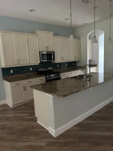 a kitchen with kitchen island granite countertop a sink a counter space and cabinets