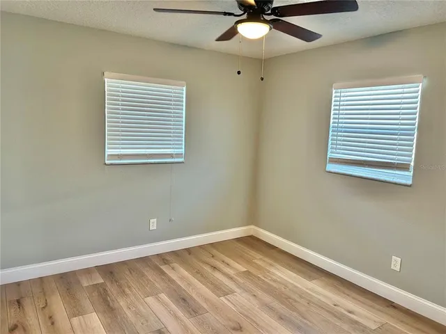 an empty room with a window and a fan