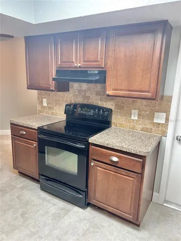 a kitchen with granite countertop wood cabinets and a stove top oven