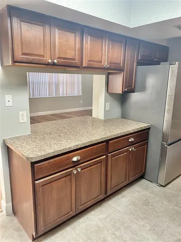 a kitchen with granite countertop a refrigerator and cabinets